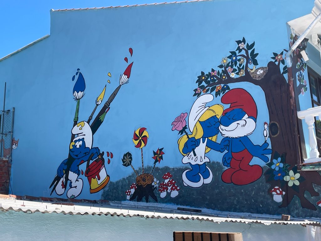 Kolorowy mural ze Smerfami na ścianie budynku w andaluzyjskim Juzcar