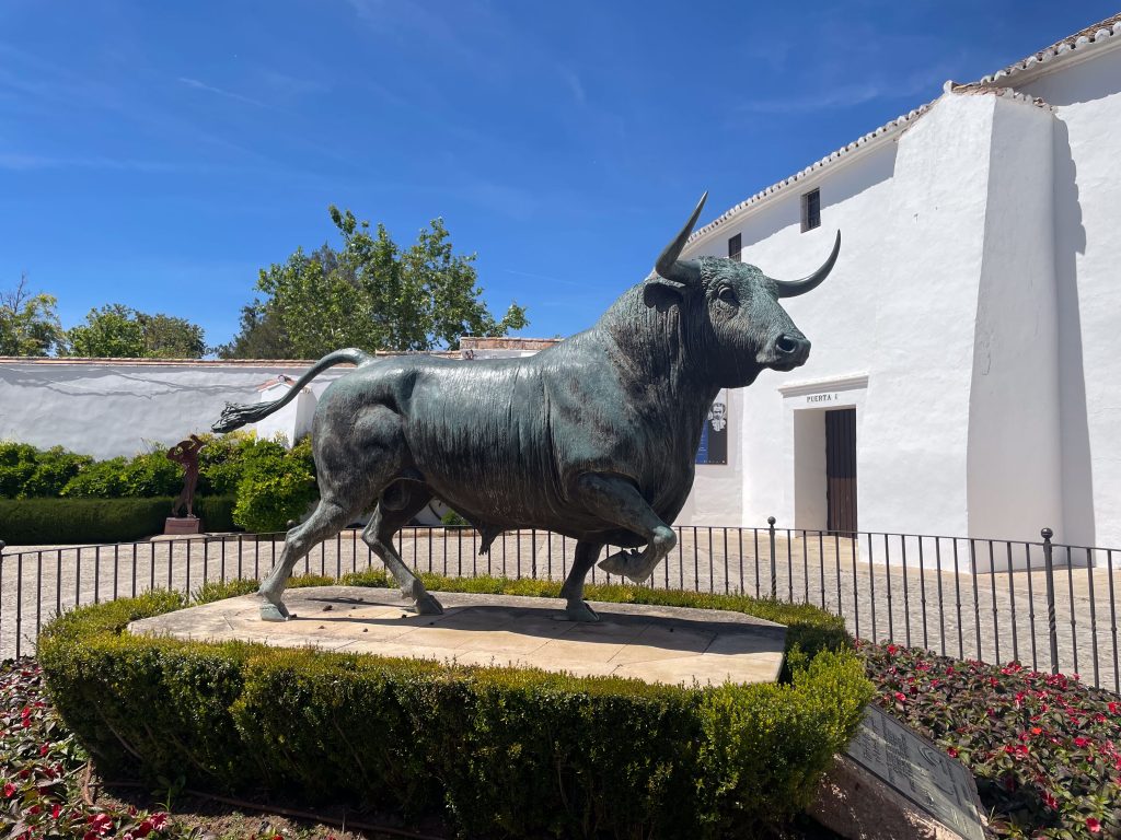 Majestatyczna rzeźba byka na tle białych budynków w Rondzie