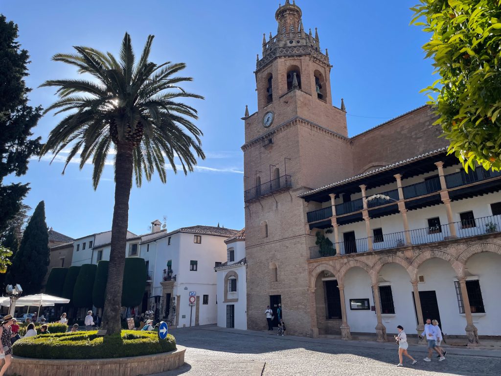 Malowniczy plac z wieżą kościelną i palmą w centrum Rondy, Hiszpania