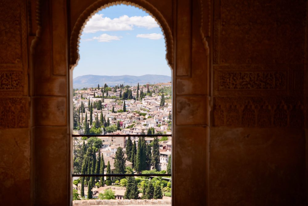 Panorama Granady przez zdobione łuki pałacu Alhambra w Hiszpanii