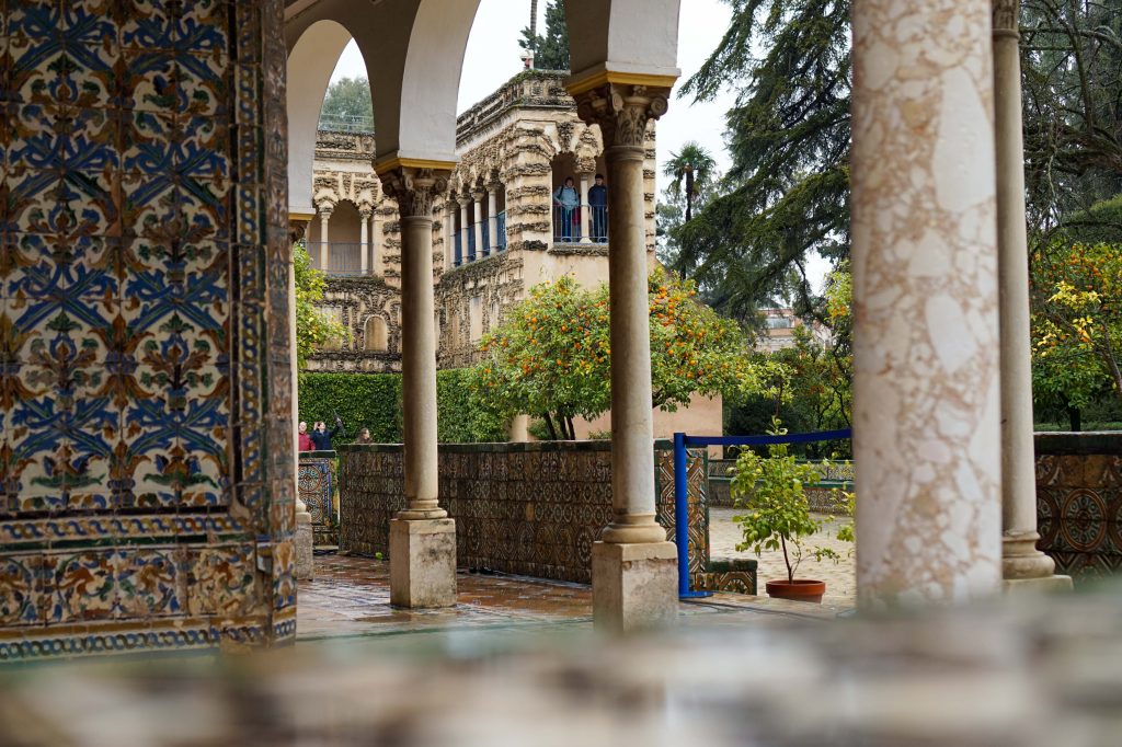 Widok przez kolumny na mauretańską architekturę Alcázaru w Sewilli